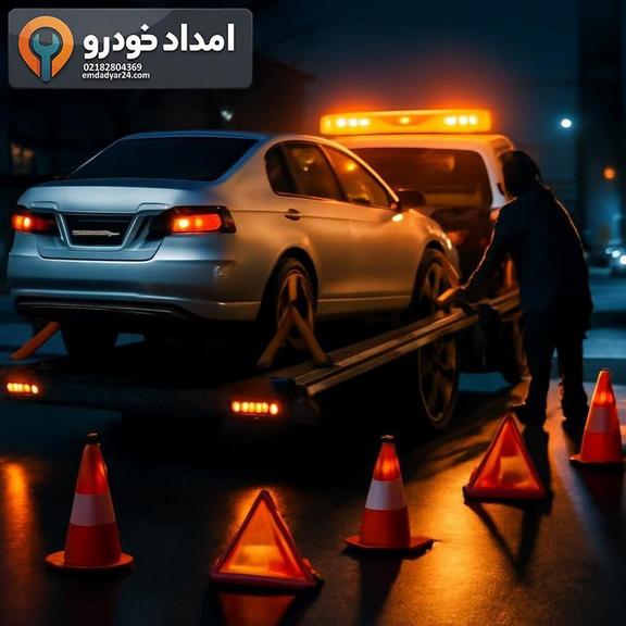 بارگیری ایمن خودرو روی کفی‌بر در شب با چراغ گردان روشن و علائم هشدار